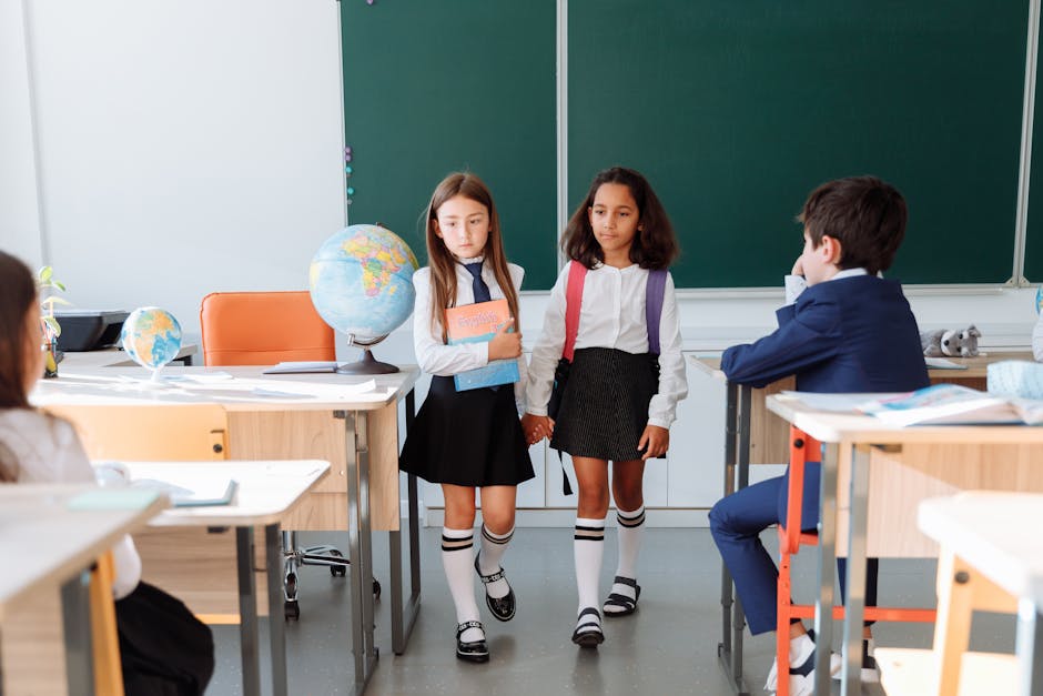 Two girls walking hand in hand inside a classroom with students and a globe.