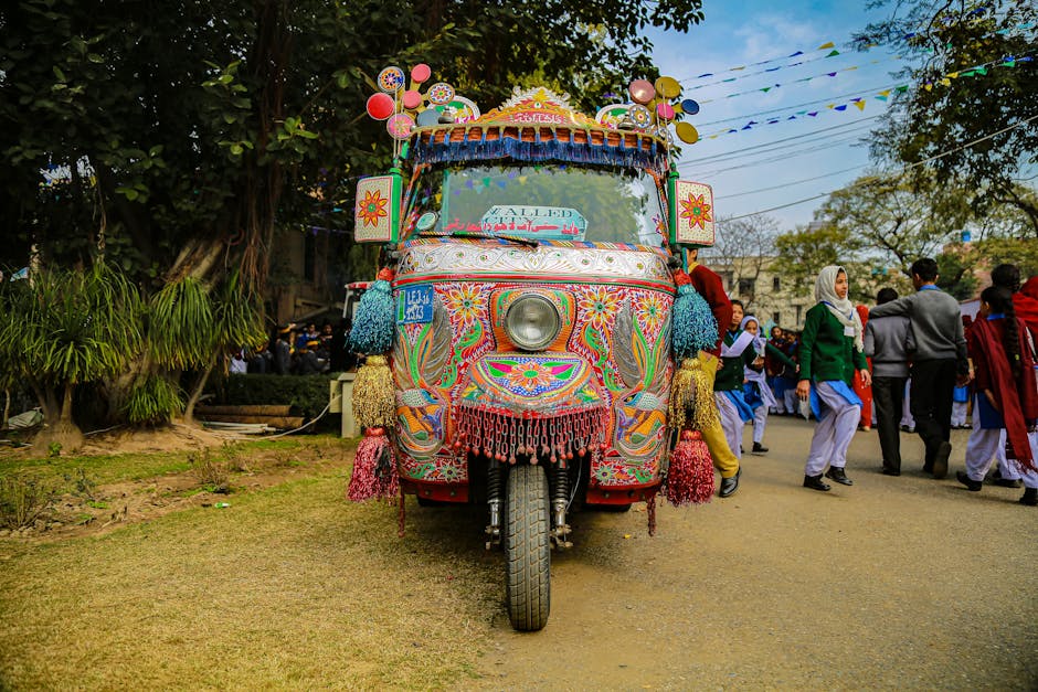 Vibrant tricycle adorned with intricate designs on a busy street scene in Pakistan.