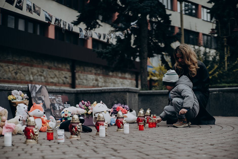 Mother and child paying tribute with candles and gifts at a memorial in Ukraine, showcasing remembrance and emotional connection.