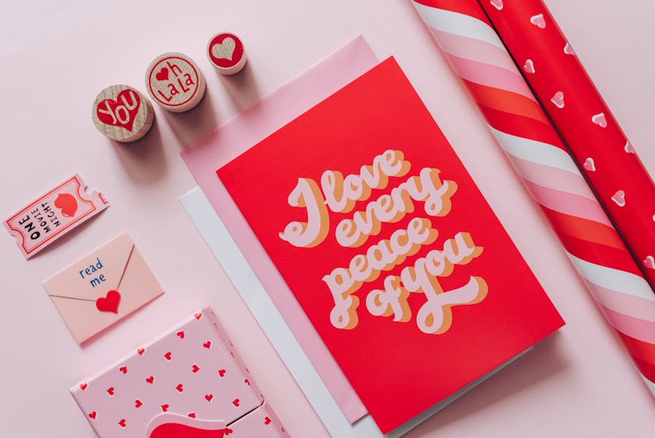 Flat lay of romantic cards and gift wraps with love messages on a pink background.
