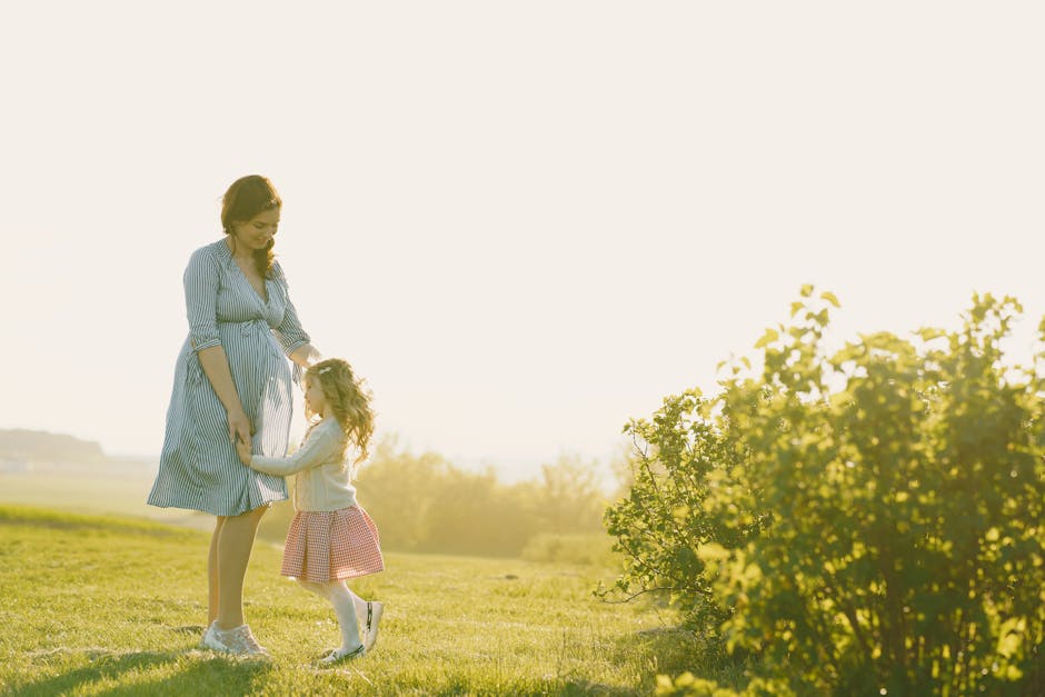 Pregnant mother with daughter enjoying a sunny day outdoors.
