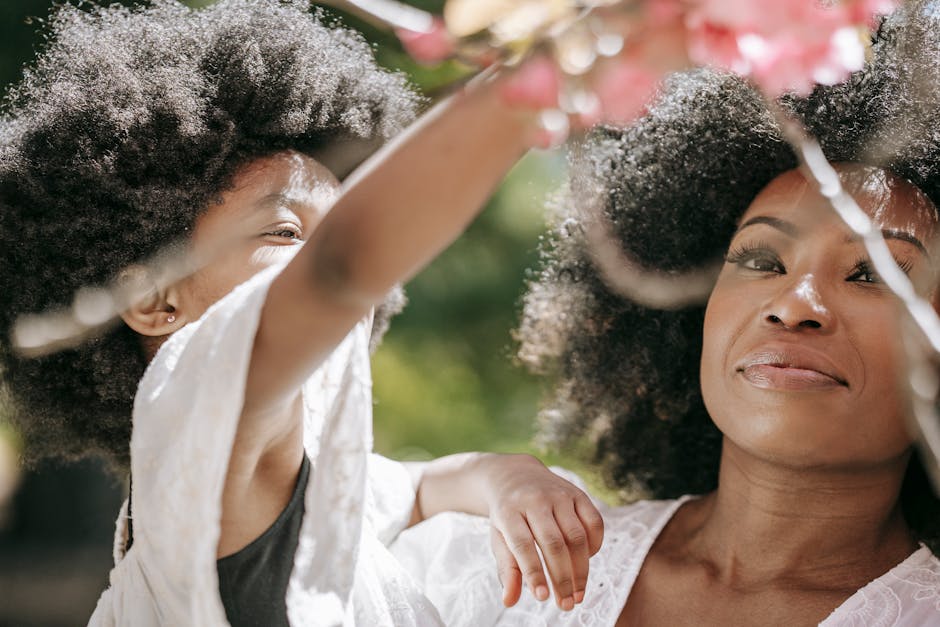 A heartwarming close-up of a mother and daughter enjoying cherry blossoms outdoors.