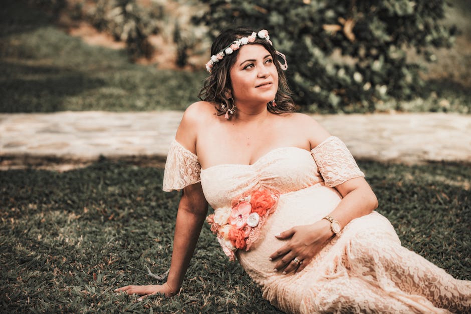A beautiful and elegant maternity shoot in a park setting, featuring a pregnant woman in a lace dress and flower crown.