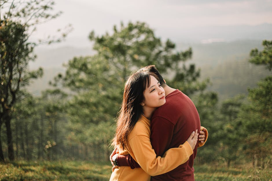 Young couple hugging peacefully in a forested area with sunlight.
