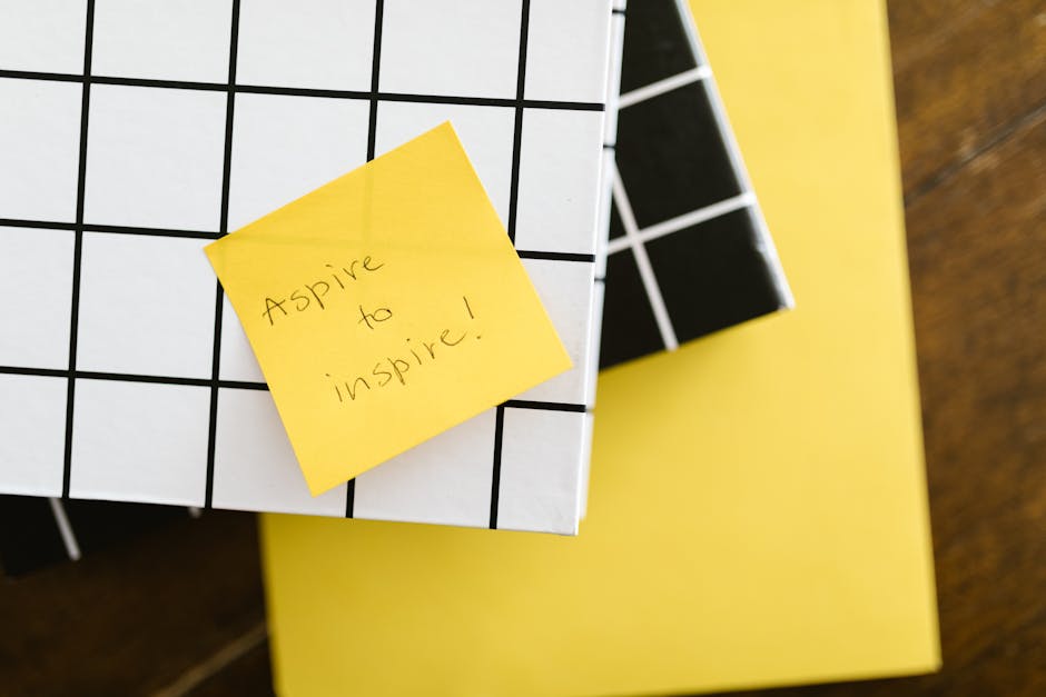 Motivational quote 'Aspire to inspire' on a sticky note placed on books. Minimal and inspirational visual.