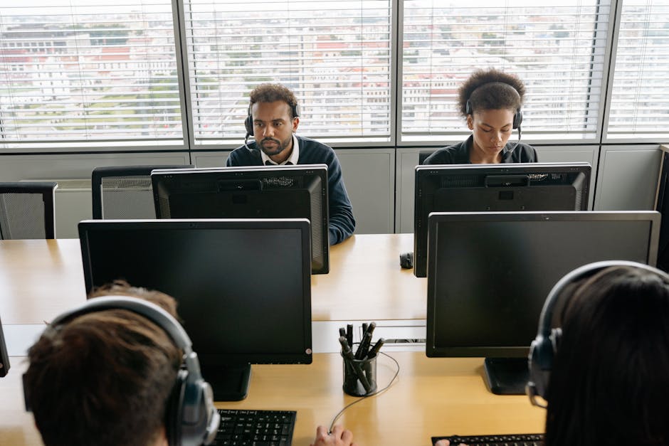 Group of call center agents working on computers in an office environment.