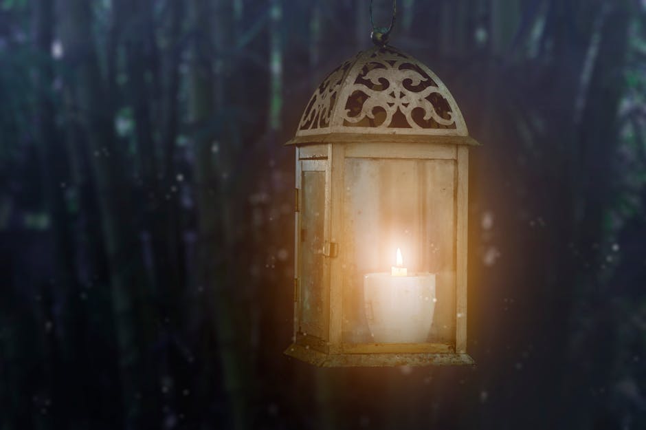 Warm glow of a candle inside a vintage lantern against a blurred dark background.