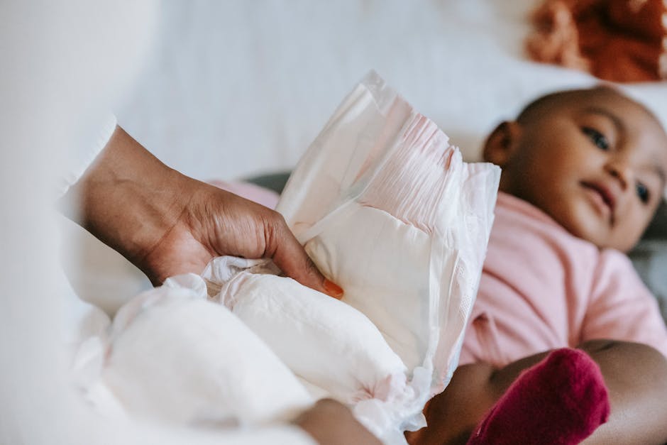 A mother gently changes her baby's diaper in a calm, cozy home setting.