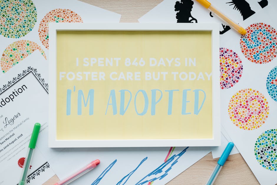 Framed adoption announcement with art and pens, celebrating new beginnings.