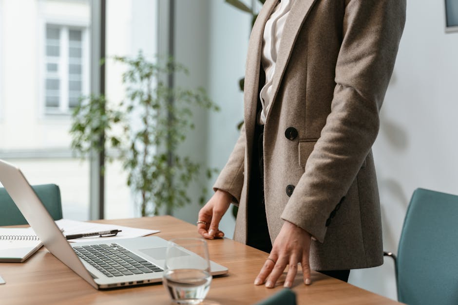 A professional businesswoman in a stylish office environment with a laptop and notes.
