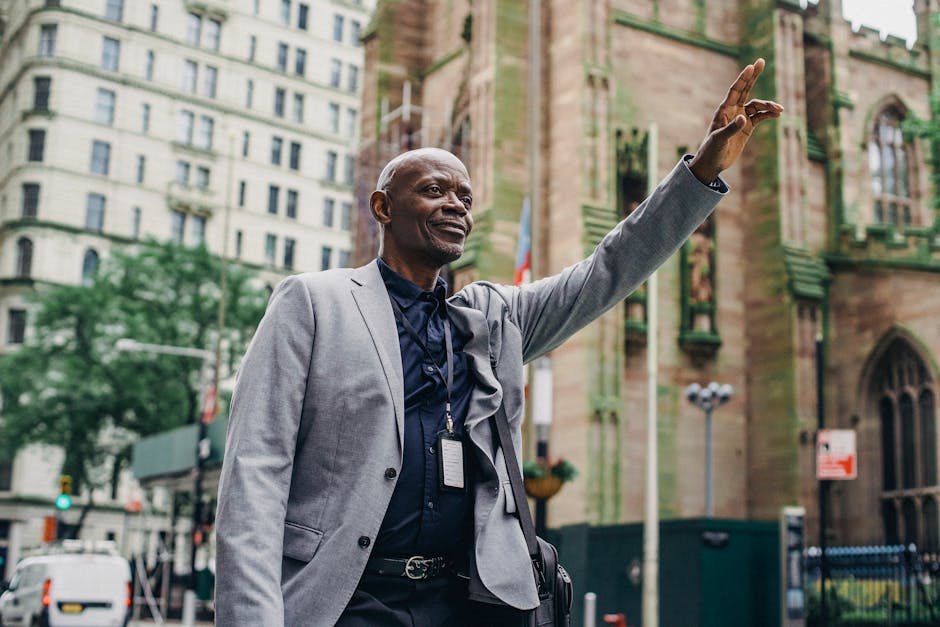 From below of African American male in business suit with hand up on blurred background of buildings