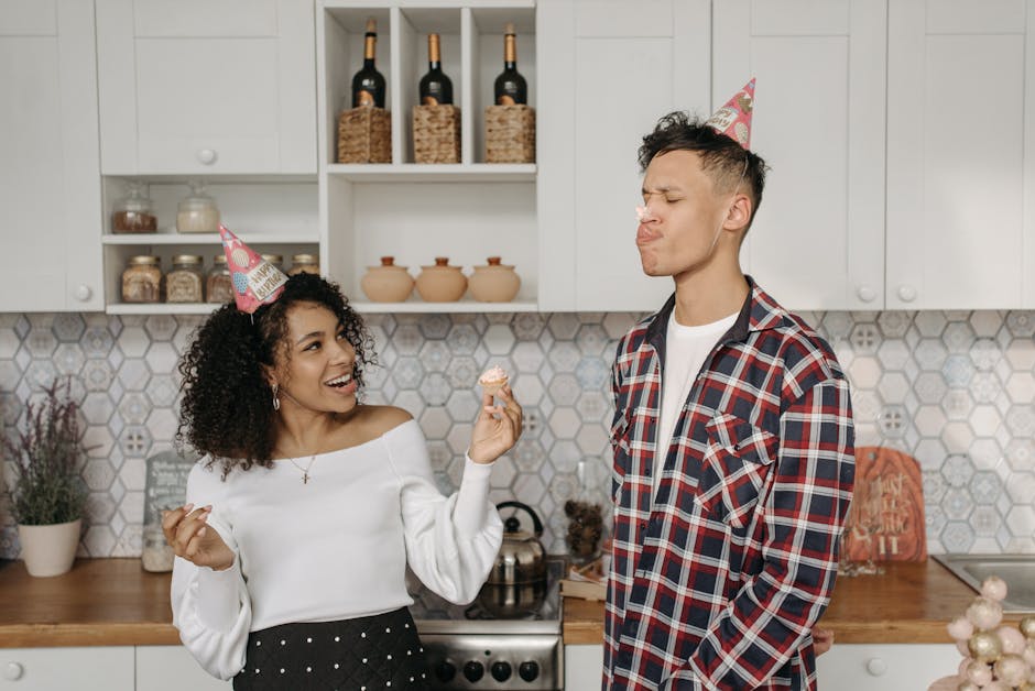 A joyful birthday celebration in a kitchen with friends wearing party hats and enjoying cupcakes.