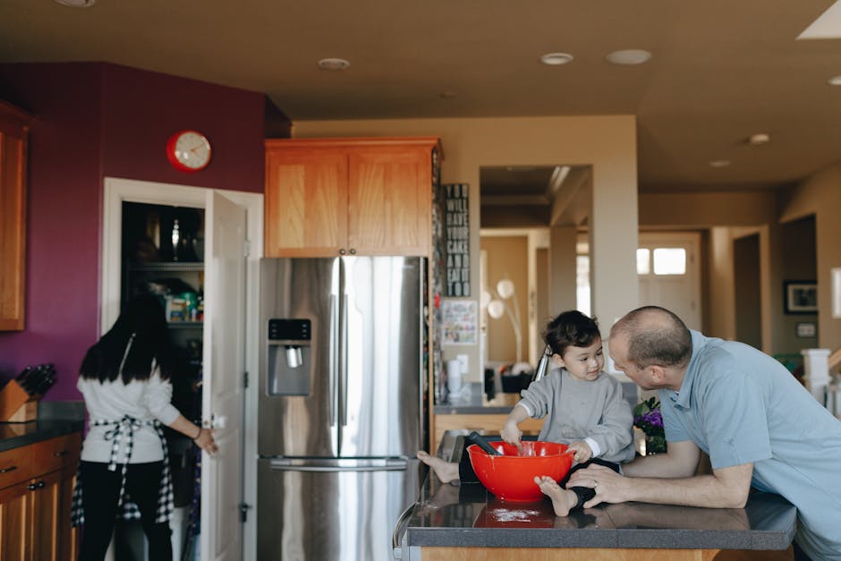 Father and child bonding in the kitchen while mother cooks, creating a warm family moment.
