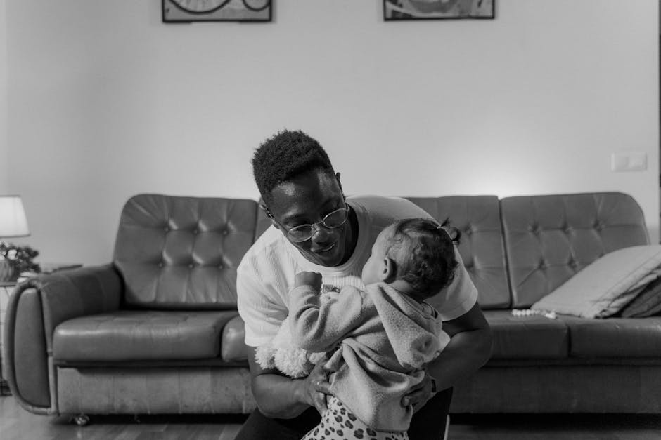 A touching black and white image of a father holding his daughter indoors.