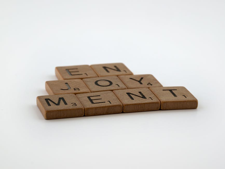 Wooden Scrabble tiles forming the word 'Enjoyment' on a white background.