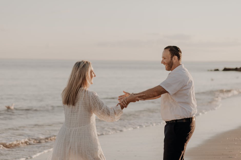 A couple holds hands on a serene beach, symbolizing love and connection.