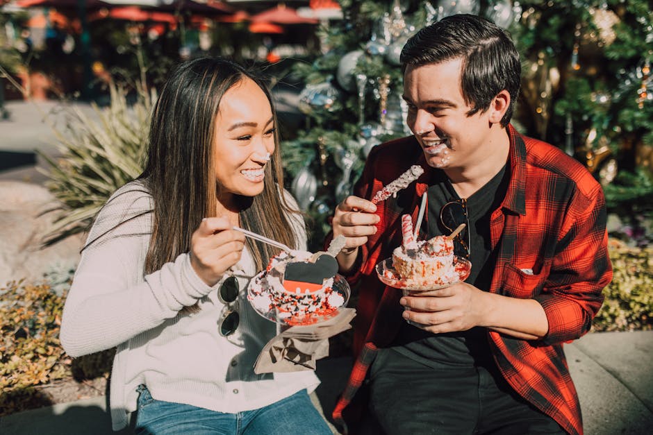 A joyful couple sharing a sweet dessert treat outdoors on a sunny day.