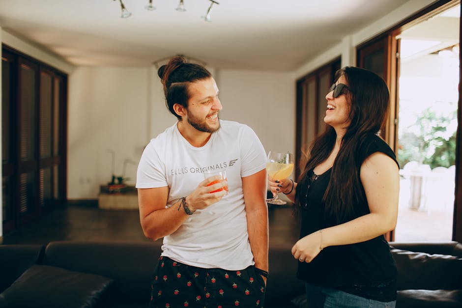 Cheerful couple laughing and enjoying drinks in a modern living room setting.