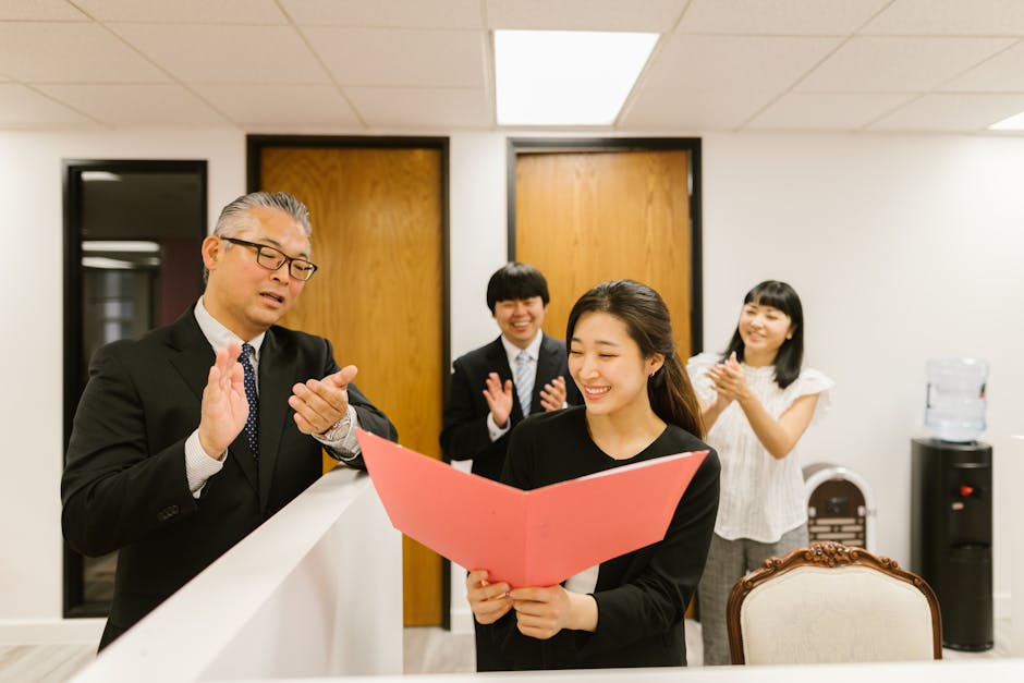 A diverse group of professionals clapping and celebrating in a modern office environment.