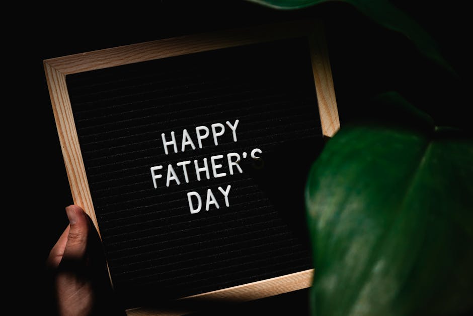 Letter board with 'Happy Father's Day' message held by hand, surrounded by leaves.