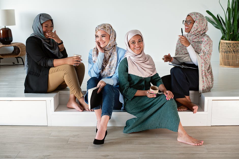 A group of diverse women in hijabs collaborate and enjoy coffee in a modern office.