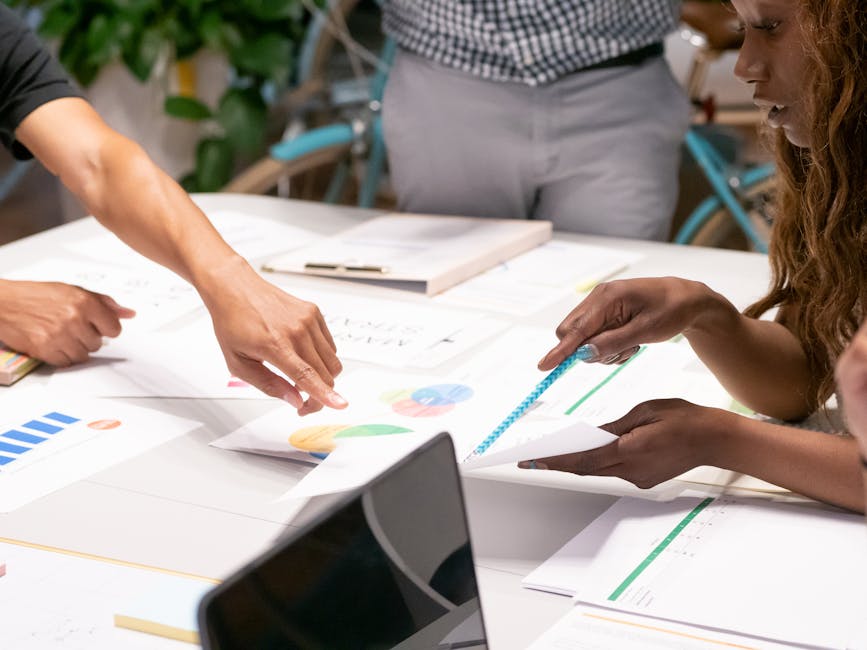 A diverse team collaborating on business strategies with charts and documents in an office setting.