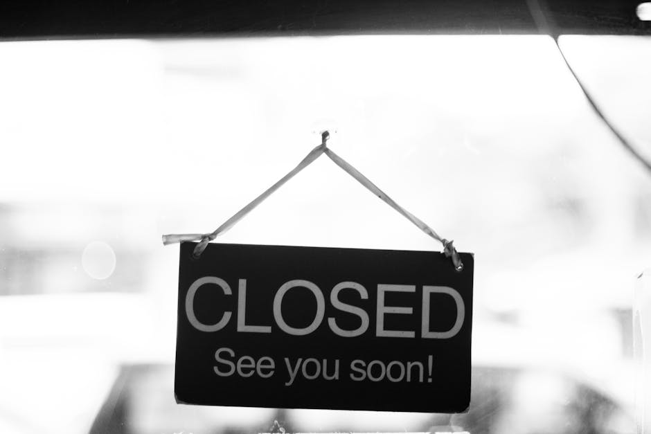 Black and white photo of a closed sign hanging in a shop window.