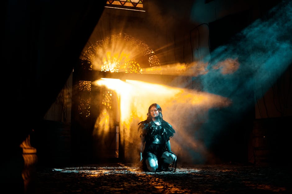 A young woman kneels in dramatic light and shadows, creating an ethereal atmosphere.