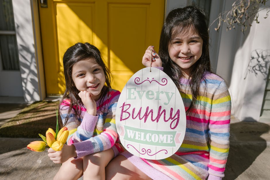 Two girls enjoying Easter with colorful outfits and decorations, holding a cheerful sign.