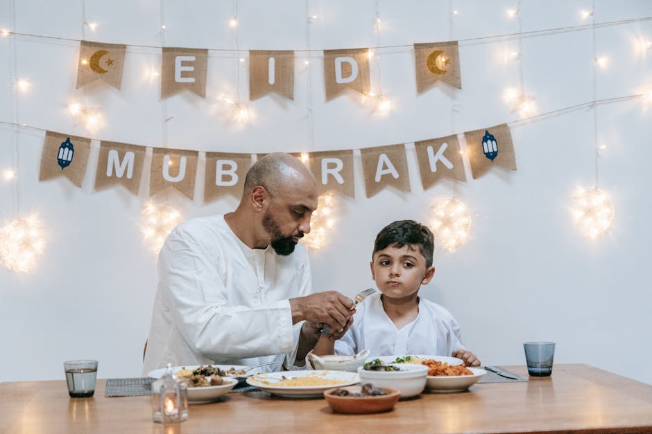 A father and son enjoying a festive Eid meal together indoors with decorations.