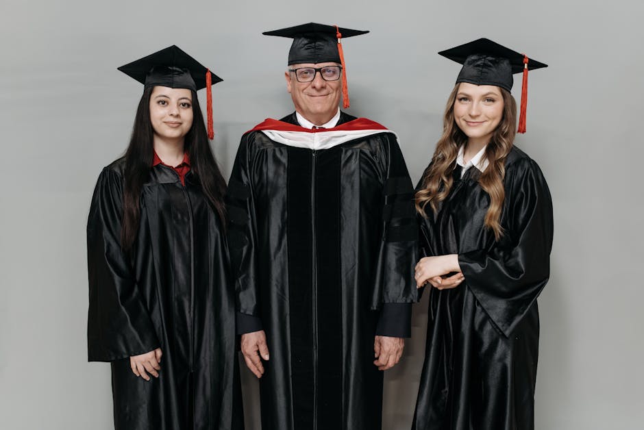 Three graduates posing with pride in graduation gowns and caps.