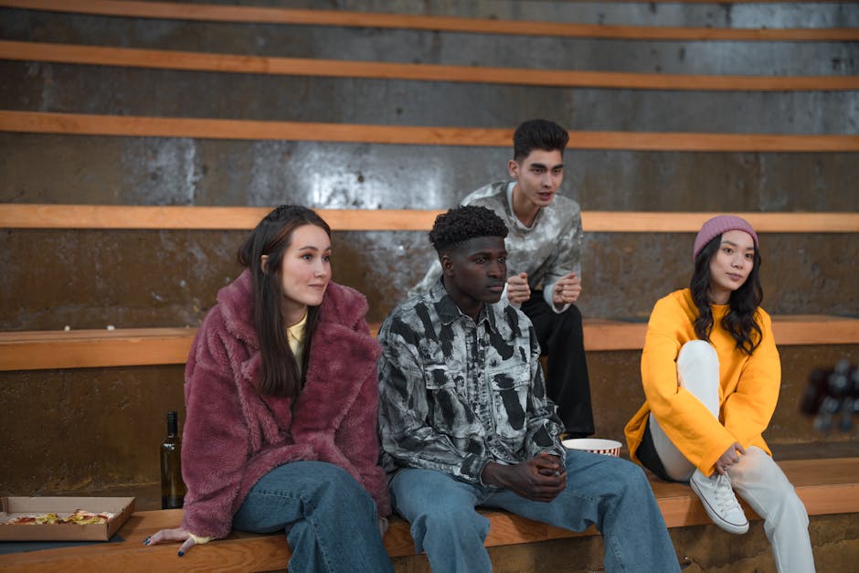 A diverse group of young adults sitting on bleachers enjoying their time together.