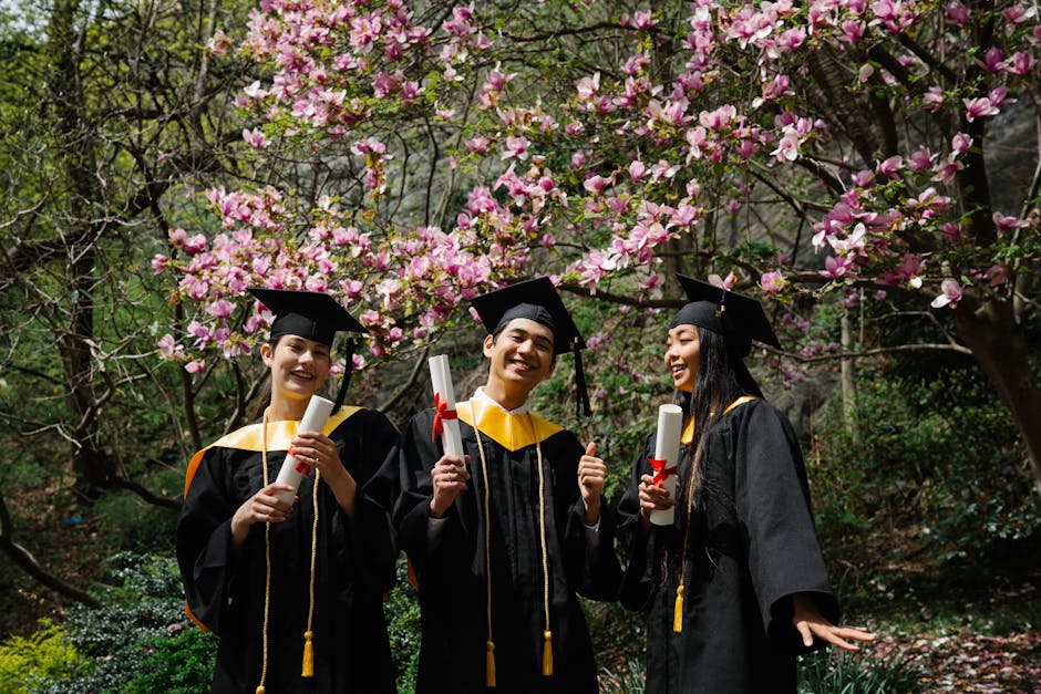 Happy graduates celebrate in a blooming garden, holding diplomas outdoors.