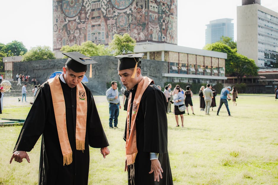Young men in graduation gowns celebrating outdoors at a university campus.