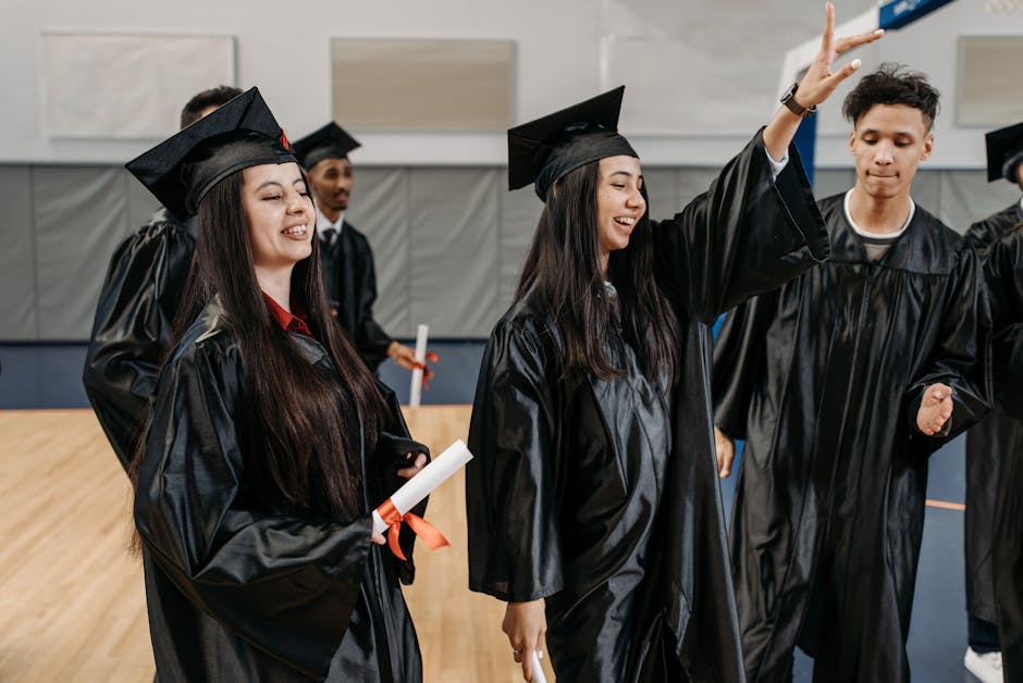 Group of graduates celebrating in caps and gowns indoors, expressing happiness and achievement.