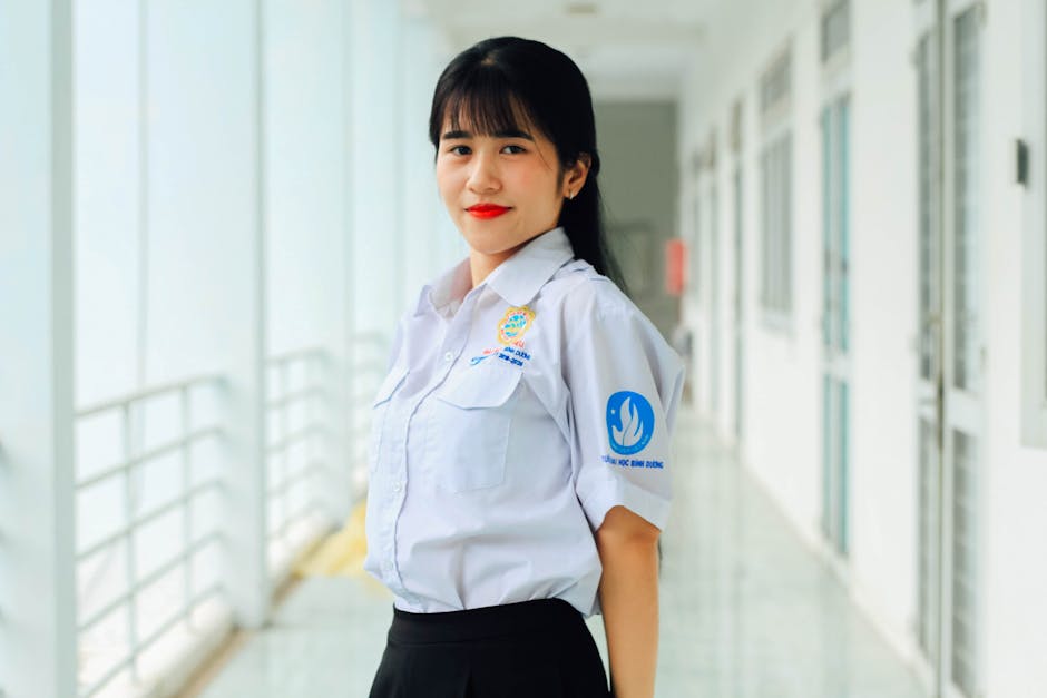 Asian woman in school uniform smiling indoors, showcasing confidence and positivity.
