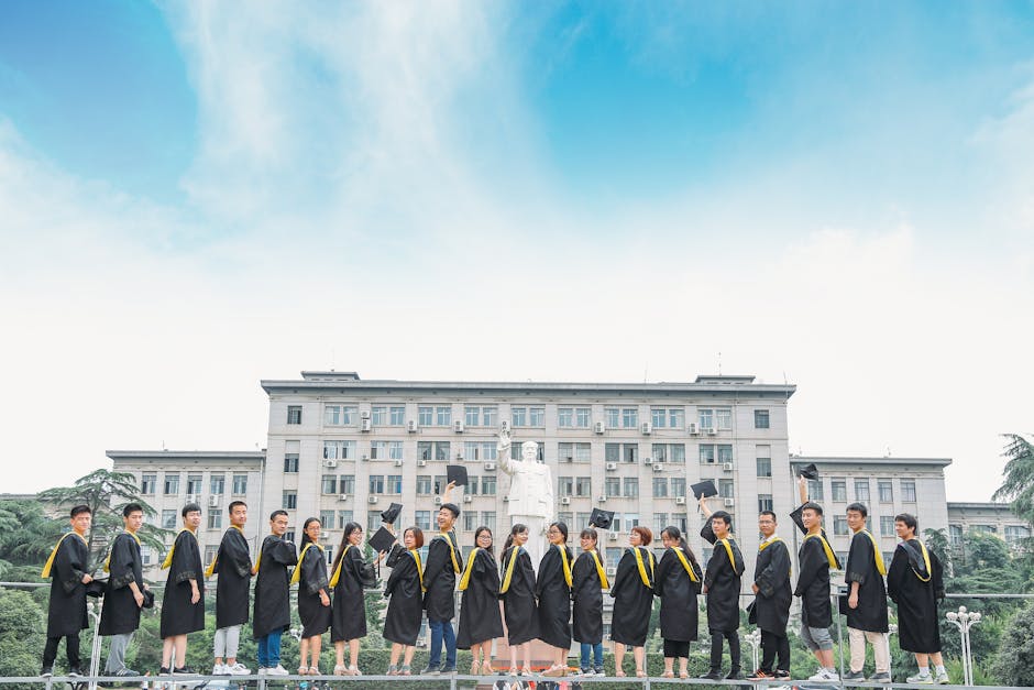 Group of graduates in caps and gowns celebrating outside a university building.