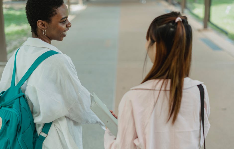 Two young women enjoying a casual conversation while walking outdoors.