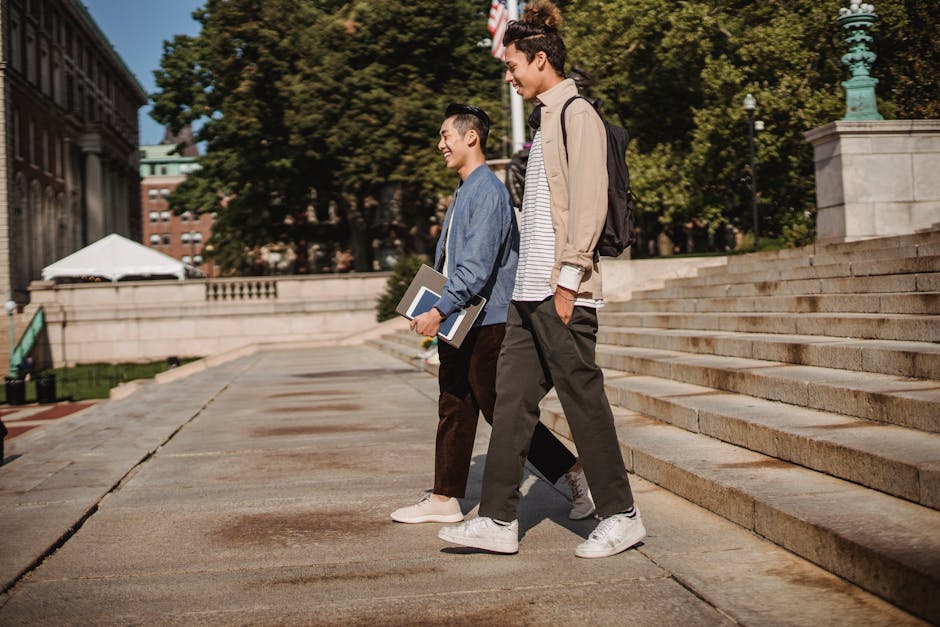 Side view full body of positive diverse students with backpack and documents in folder walking on stairway