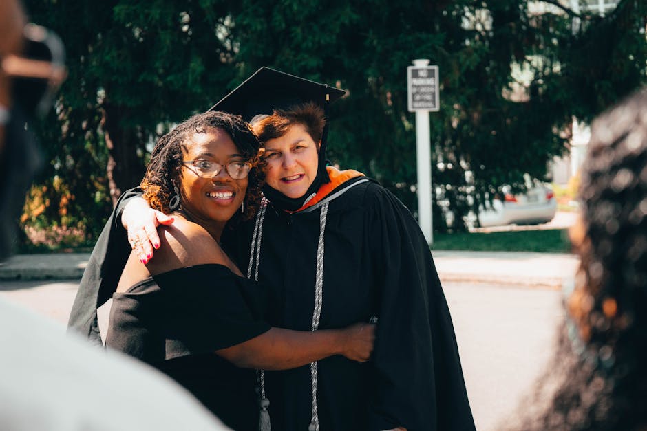 Two graduates embrace in celebration on a sunny day, sharing a moment of achievement and togetherness.