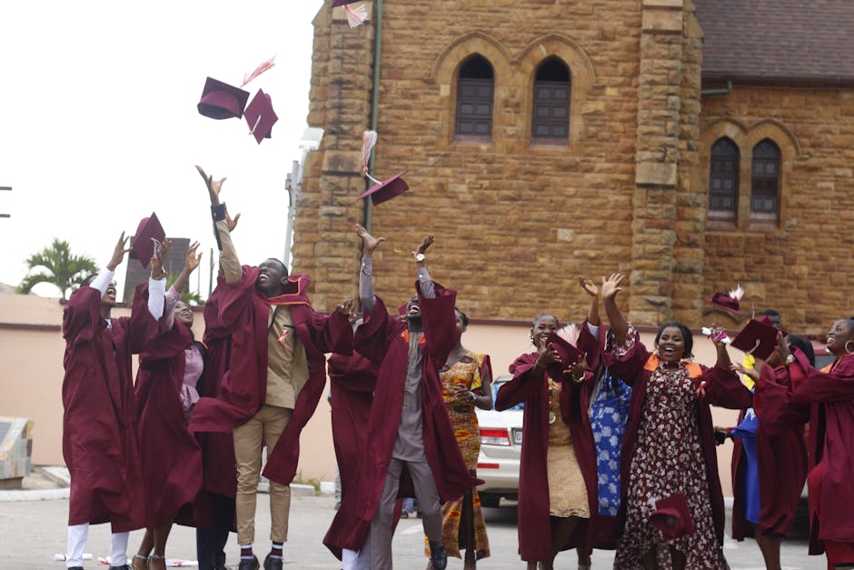 A group of young graduates celebrating and tossing their caps outdoors.