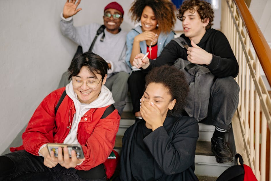 Diverse group of young students sharing a joyful moment while taking a selfie together on staircase.