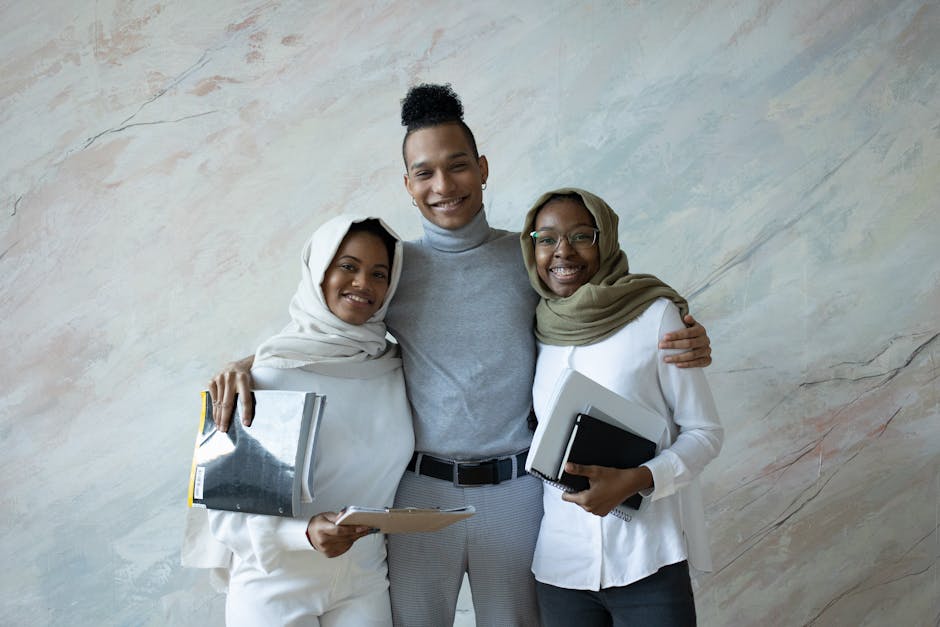 A diverse group of students embraces while holding notebooks, showcasing friendship and cooperation.