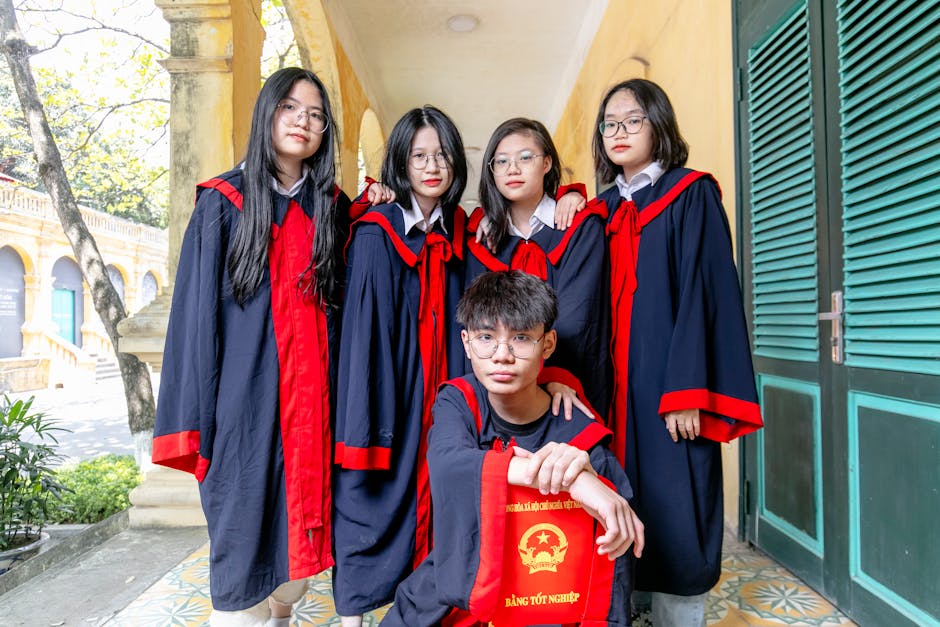 Five young graduates in academic regalia posing outdoors, celebrating their achievement.