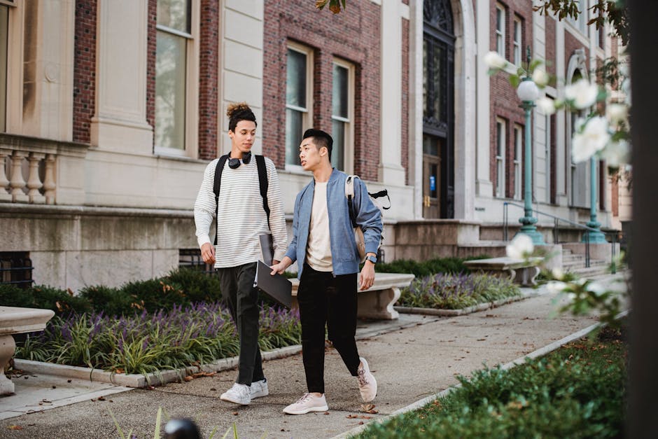 Two young men walking and chatting on a university campus path.