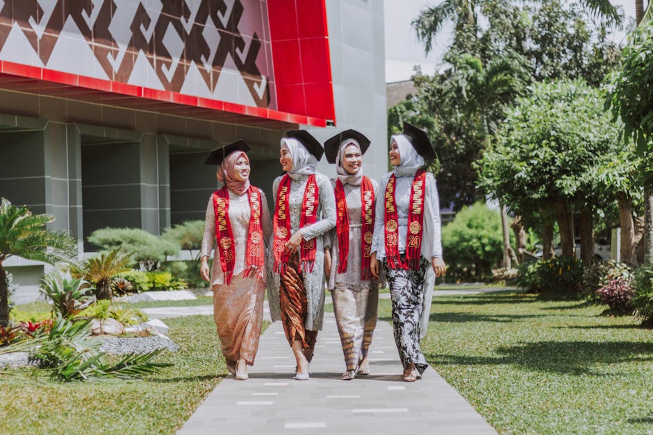 Four women in traditional attire celebrate graduation outdoors in Bandar Lampung, Indonesia.