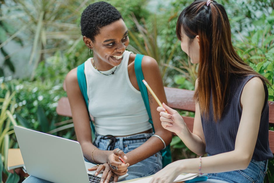 Students collaborating outdoors with a laptop, embodying teamwork and diversity in education.