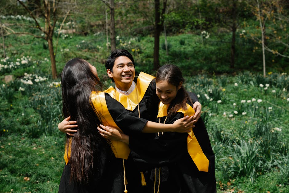 Happy graduates in gowns embracing outdoors, capturing a moment of achievement and friendship.