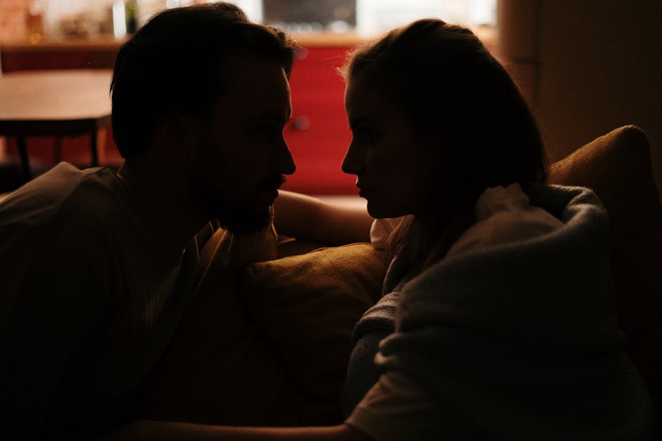 A cozy moment shared by a couple in a dimly lit home environment.