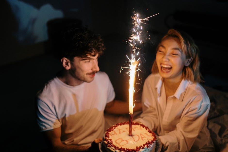 A couple celebrates with a birthday cake featuring a sparkling candle, sharing laughter and joy.